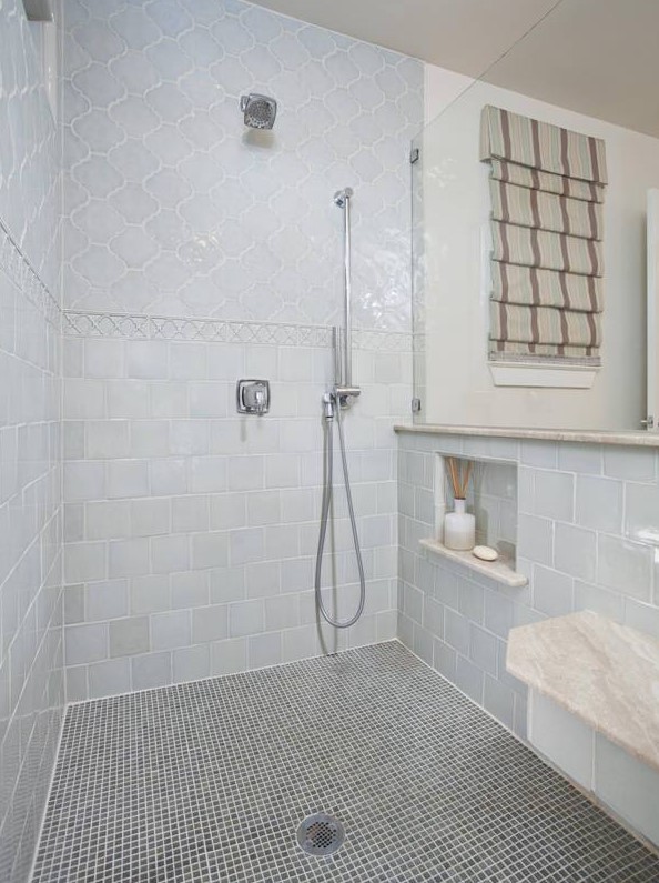 a large shower space done with blue arabesque and square tiles, with small blue tiles on the floor is a beautiful nook