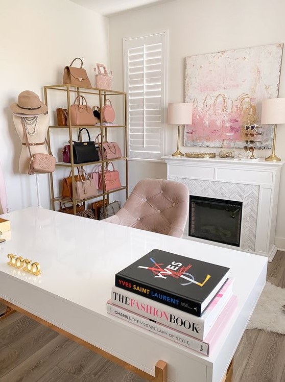 a lovely cloffice with a marble clad fireplace, a pretty artwork, a stand with beautiful bags, a desk and a blush chair is amazingly girlish