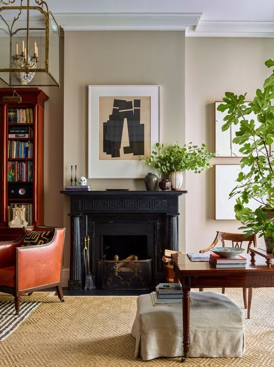 a lovely home office with neutral walls, a black fireplace, a dark stained desk and a chair, a rich-stained bookcase and a chair plus greenery