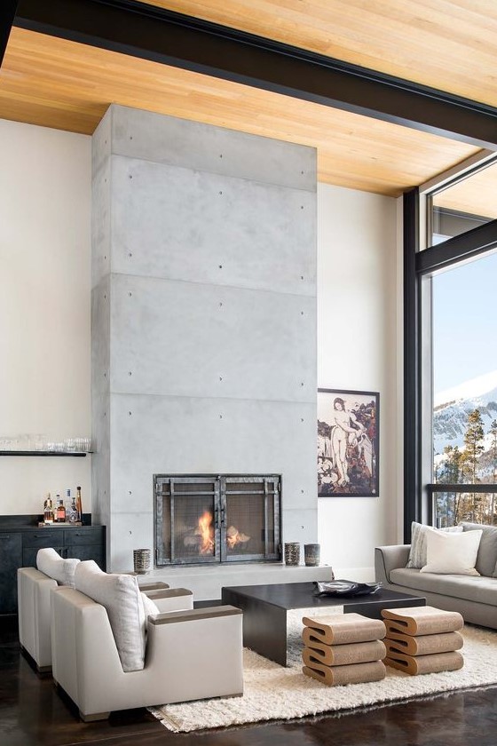 a luxurious living room with neutral furniture, catchy stools and a black table, a concrete fireplace with metal doors