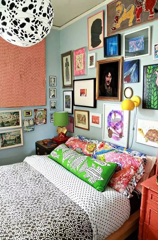 a maximalist gallery wall in various bright colors, with mismatching frames taking two walls looks very bold and cool