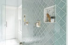 a modern bathroom with neutral tiles on the floor and a blue arabesque tile accent wall with niches for storage is a very stylish and cool idea