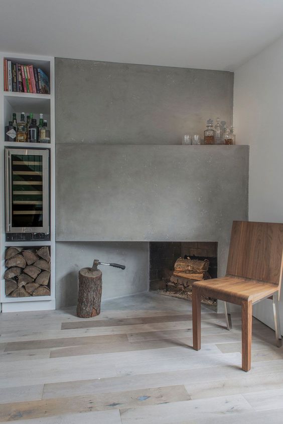 a modern nook with a corner concrete fireplace, a wooden chair, built-in shelves, a neutral floor and a tree stump
