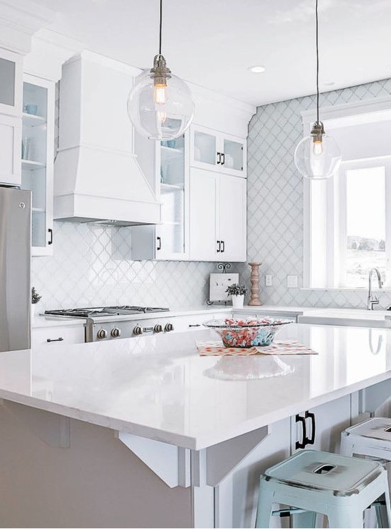 a modern white kitchen with black handles, a large white hood, a white arabesque tile backsplash and a wall is elegant