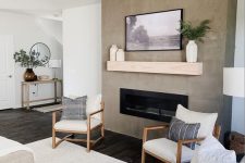 a neutral farmhouse living room with a concrete fireplace, neutral seating furniture, neutral textiles, a wooden mantel and an artwork