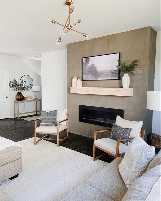 a neutral farmhouse living room with a concrete fireplace, neutral seating furniture, neutral textiles, a wooden mantel and an artwork