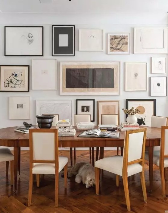 a neutral vintage dining room with a stained table and creamy chairs, a large free form gallery wall and some dried blooms