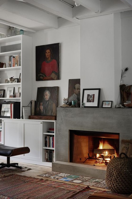 a sophisticated living room with a concrete fireplace and lots of artworks and books around it is welcoming