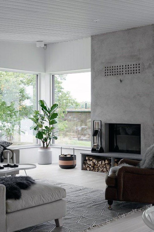 a stylish contemporary living room with a concrete fireplace with firewood storage and lots of natural light