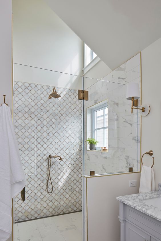 a stylish contemporary shower with white marble and arabesque tiles with copper grout, copper fixtures and windows
