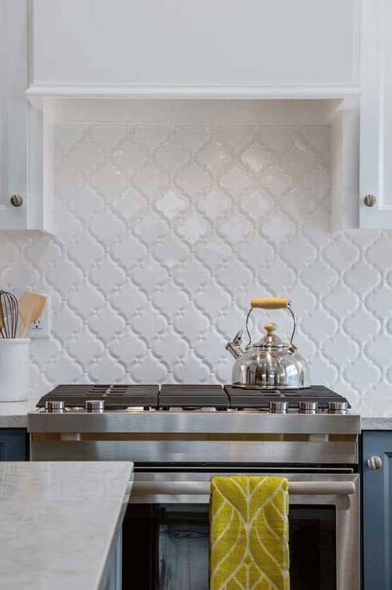 a stylish modern two-tone kitchen with white and navy cabinets, a white arabesque tile backsplash with white grout for an accent