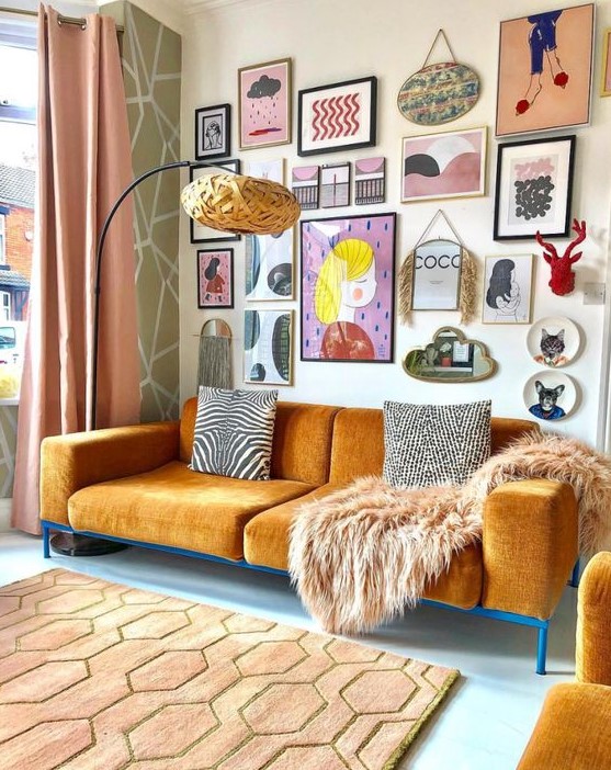 a super colorful and chic free form gallery wall with bold artworks and prints of various kinds, a mirror, decorative plates and faux taxidermy