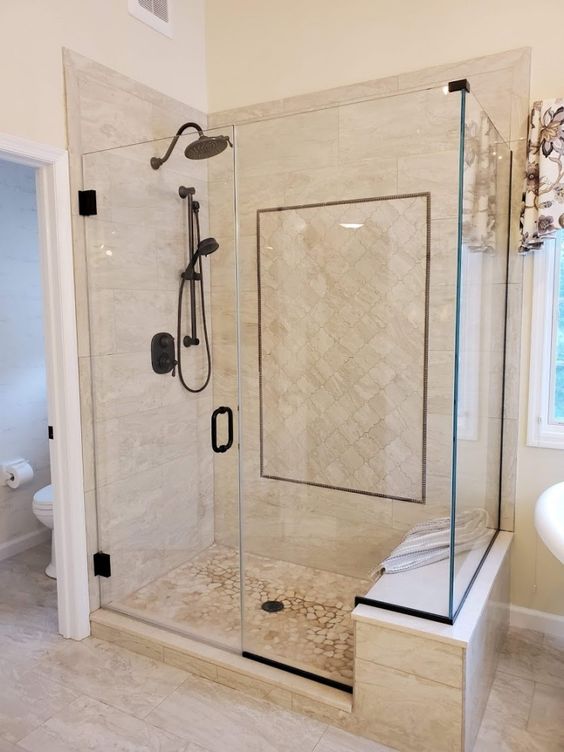 a warm-colored bathroom with tan large scale and arabesque tiles, black fixtures and black touches is lovely