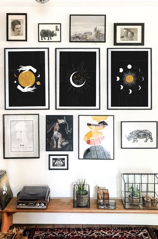 a witchy gallery wall with thin black frames, bold prints, vintage artworks and photos is a catchy idea