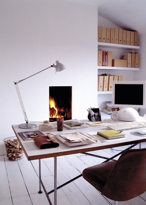 an airy home office in white, with a planked floor, a built in fireplace, a sleek and airy desk, a leather chair and built in shelves