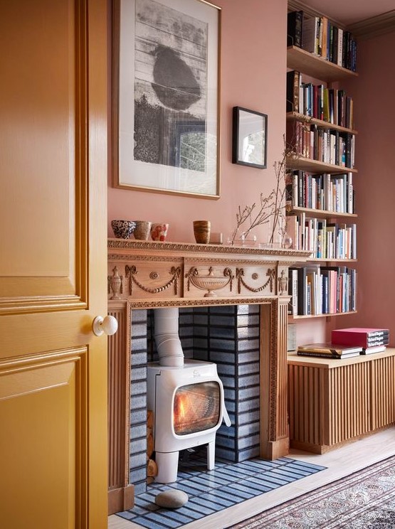 an eclectic living room with a rust-colored accent wall, a hearth in the fireplace, open shelves and a mini gallery wall