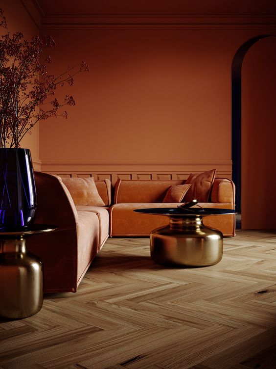 an ocher living room with orange low sofas, shiny metallic coffee tables and some grasses in a vase