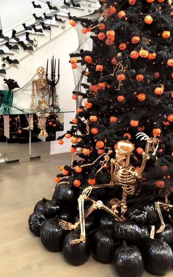 a bold and chic Halloween styled space with a Halloween tree with pumpkin lights, black pumpkins and a gilded skeleton is a fun idea