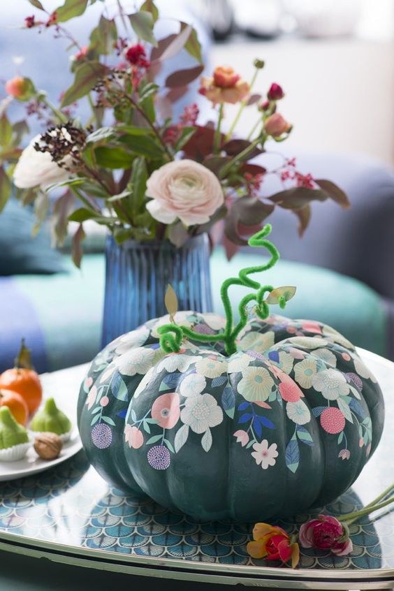 a chic black pumpkin decorated with pastel blooms and foliage is a lovely idea for a fall or Halloween space