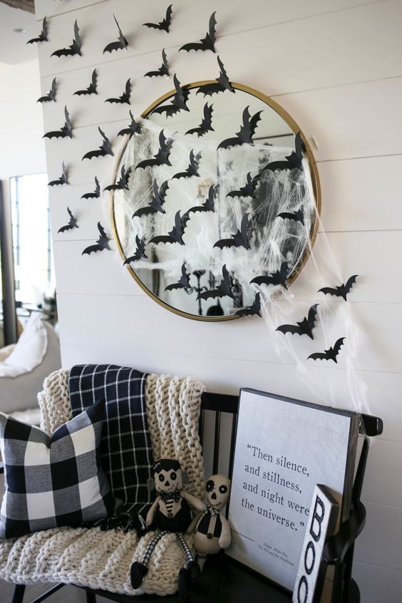 a black bench styled with blankets and pillows, with signs and scary toys plus a hautned mirror with spiderweb and black paper bats