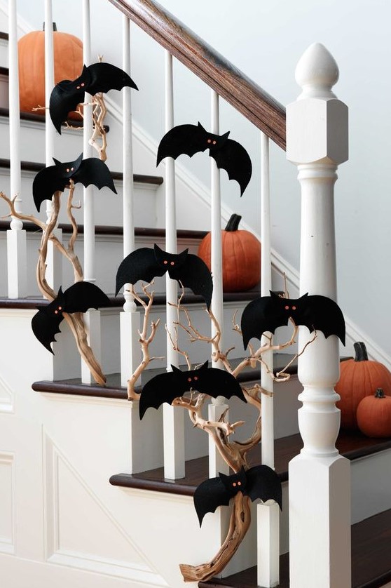 a branch covered with black paper bats with red eyes and pumpkins on the steps to style the space for Halloween easily