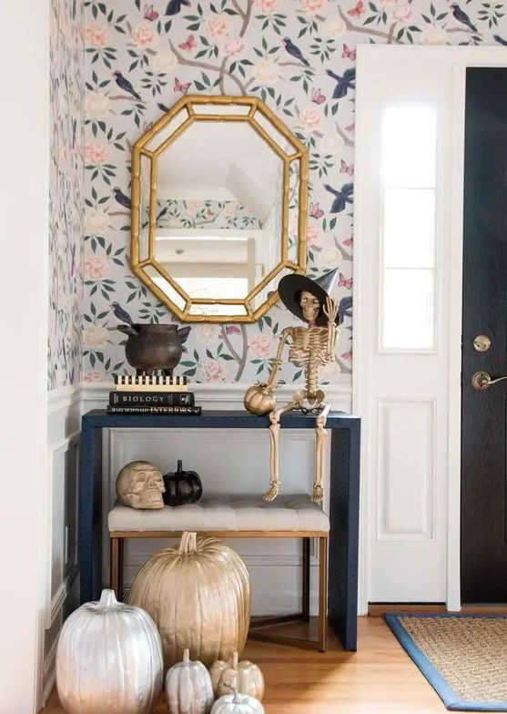 a glam Halloween console table with silver, gold and black pumpkins, a gold skeleton in a witch hat and a skull