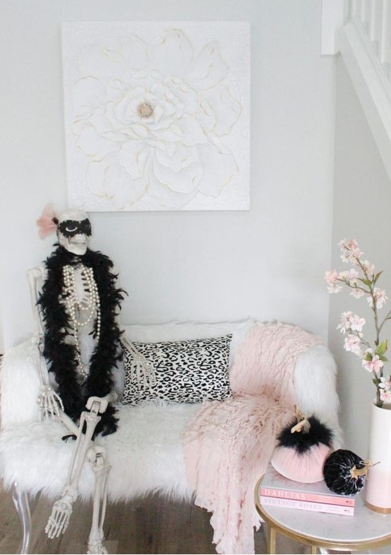 a glam nook with a skeleton dressed in jewelry and a fur scarf, with black and pink pumpkins is a romantic and cute idea