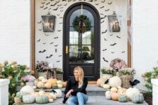 08 a farmhouse front porch done with lots of heirloom pumpkins, blooms in baskets and black paper bats covering the wall is amazing