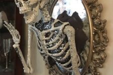 10 a scary glam Halloween decoration of a vintage mirror with a glam embellished half skeleton attached is elegant