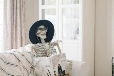12 Halloween decor with a skeleton reading a book in a hat and some pumpkins will be a great idea for your party