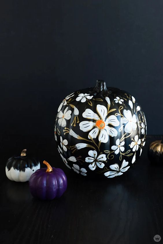 elegant Halloween pumpkins - a black one with gorgeous white blooms painted, a black and white and a purple one