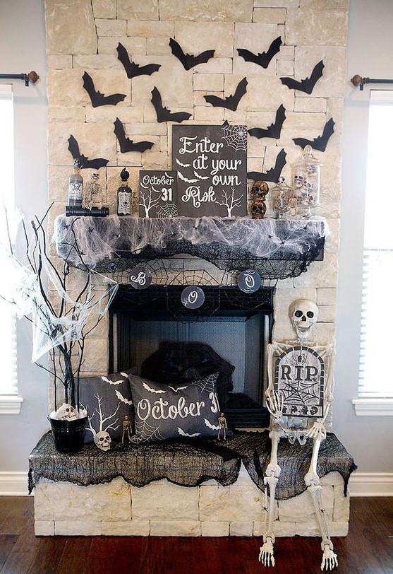 Halloween fireplace styling with bats, spider web, a skeleton, a pillow, branches and a bunting is a cool idea