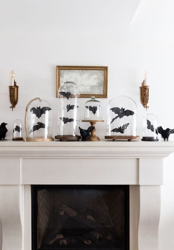 a Halloween mantel decorated with black paper bats in cloches and with blackbirds is a cool idea to go for