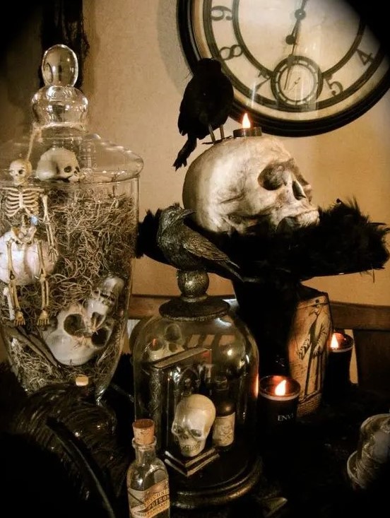vintage Halloween decor with jars and cloches with skulls and skeletons, a skull on a stand, some candles and a blackbird
