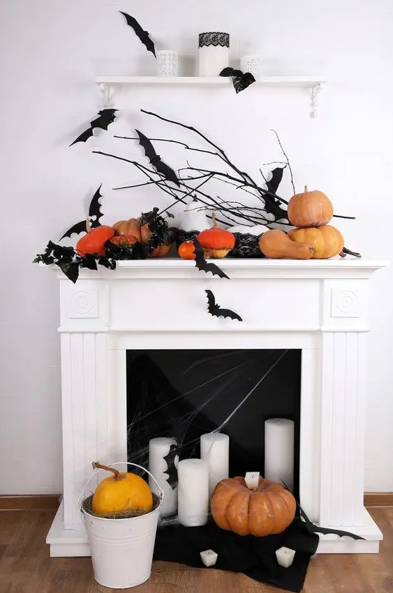 a modern Halloween fireplace with black bats, pumpkins, pillar candles and a bucket with a pumpkin