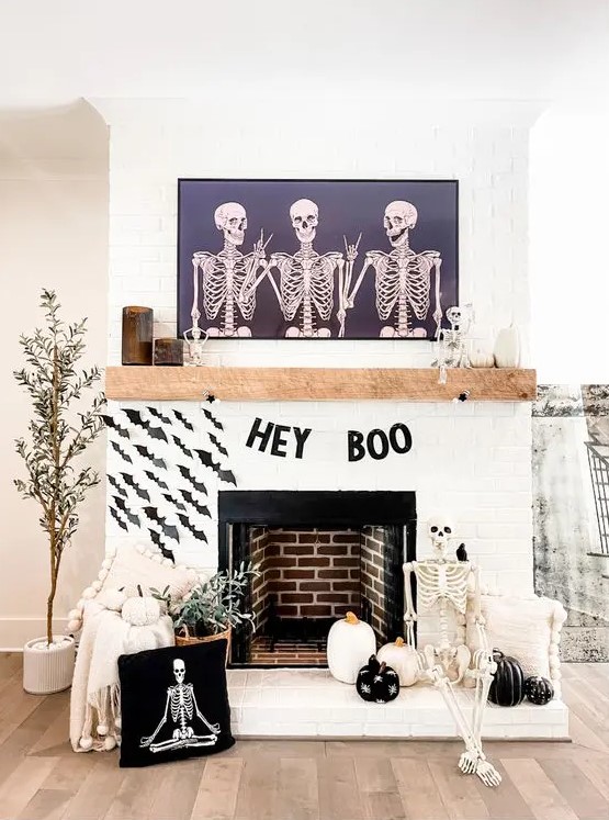 a black and white Halloween mantel with a letter banner, black paper bats, black and white pumpkins, a skeleton and potted plants