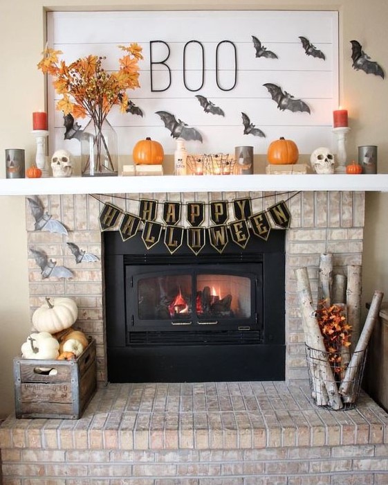 a classic rustic Halloween fireplace with grey bats, orange and grey candles, pumpkins and fall leaves