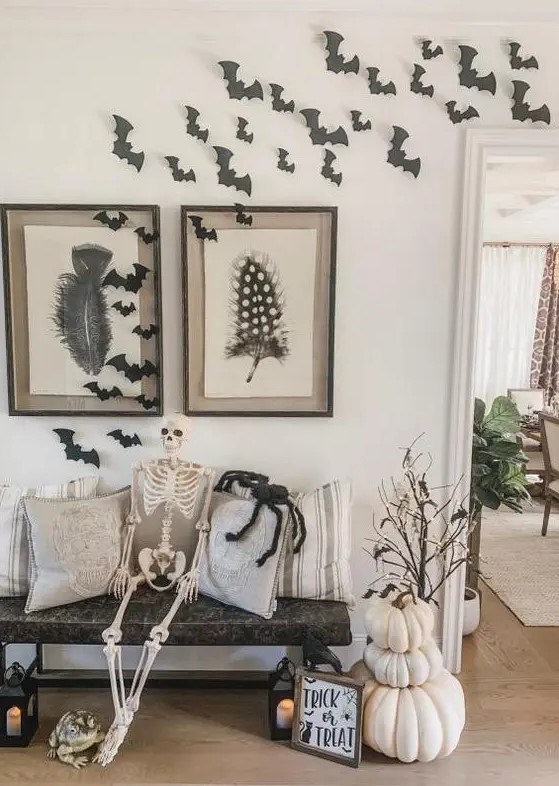 a rustic Halloween entryway with stacked white pumpkins, branches with lights, bats and a skeleton
