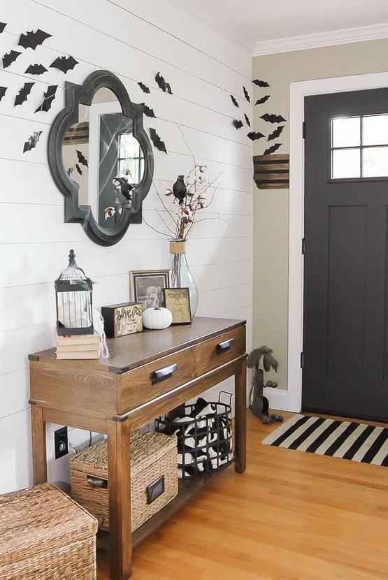 a simple farmhouse Halloween entryway with bats, black and white touches, blackbirds and some white pumpkins