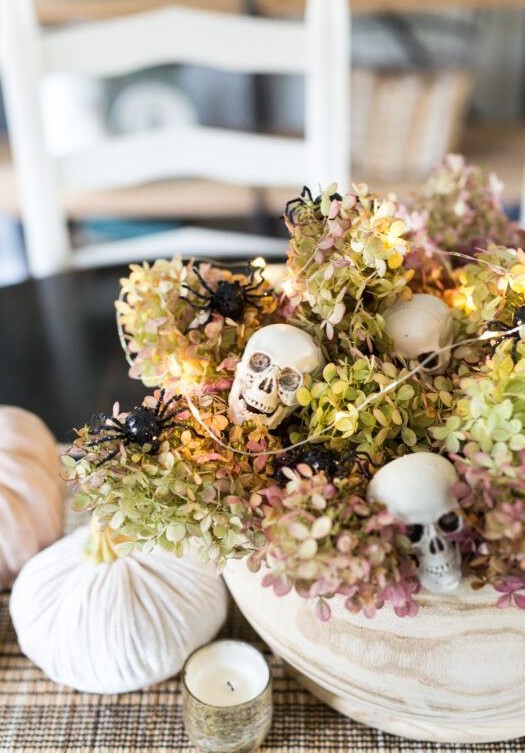 a neutral bowl with dried hydrangeas, skulls, lights and white velvet pumpkins for Halloween