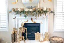 26 a white and gold Halloween fireplace with greenery, skulls, a skeleton, candles and bats
