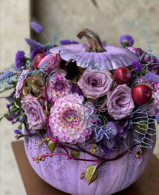 a beautiful lilac pumpkin styled with lilac, violet blooms, foliage and cherries is a lovely idea for Halloween decor