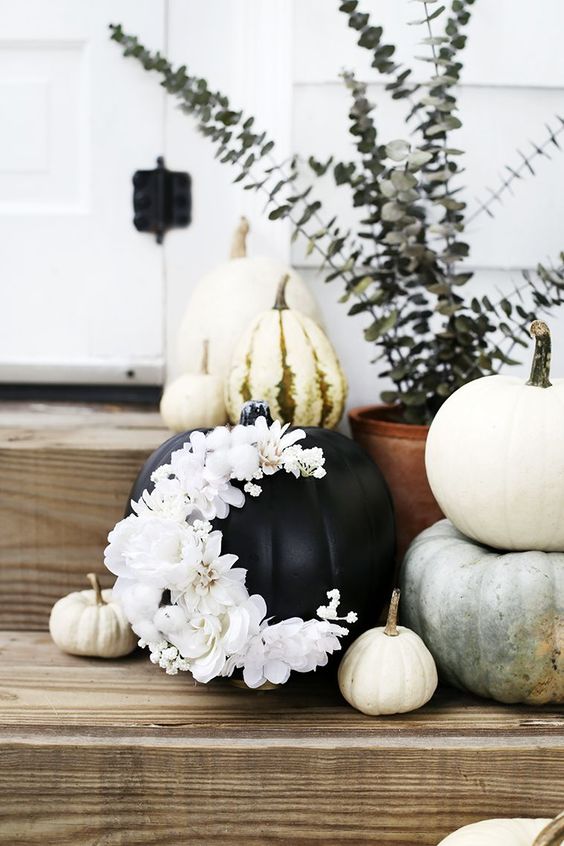 a black pumpkin decorated with gorgeous and lush white blooms forming a crescent moon looks amazing for Halloween