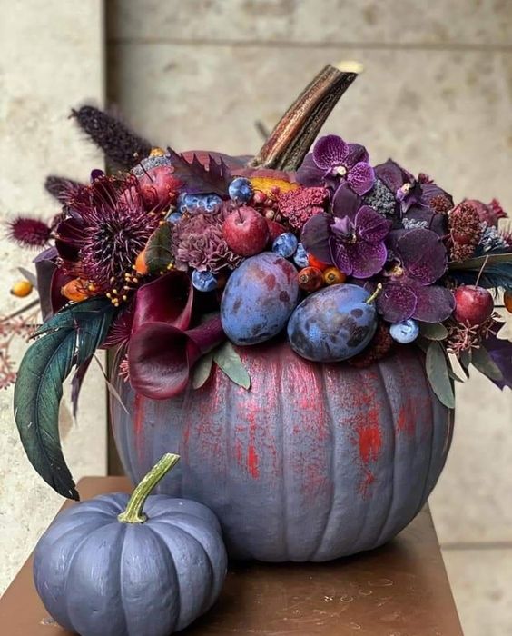 a jaw-dropping grey pumpkin decorated with dark burgundy and purple blooms, plums, berries and apples and dried grasses