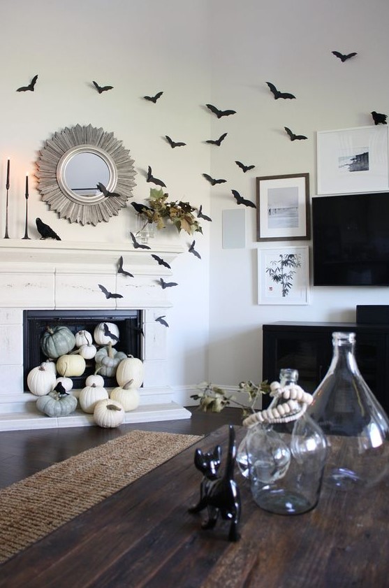 black paper bats covering the fireplace and the wall, natural pumpkins in the fireplace, black candles and blackbirds for Halloween