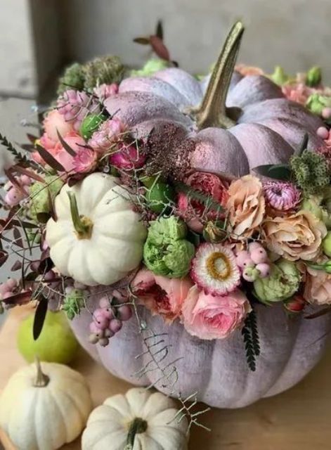 a lilac pumpkin decorated with pink, mauve and neutral blooms, berries, greenery and dark foliage and small pumpkins