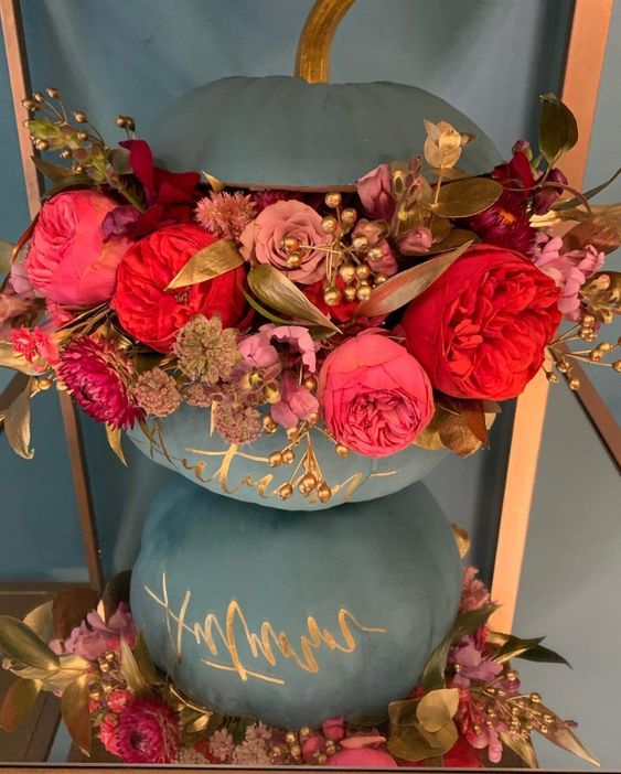 a matte grey pumpkin decorated with gold calligraphy, pink, mauve and deep red blooms, gilded leaves and berries