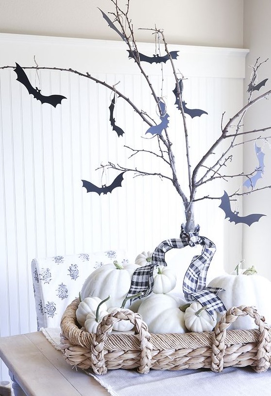 simple farmhouse Halloween decor with a basket with white pumpkins, branches with black bats attached to them