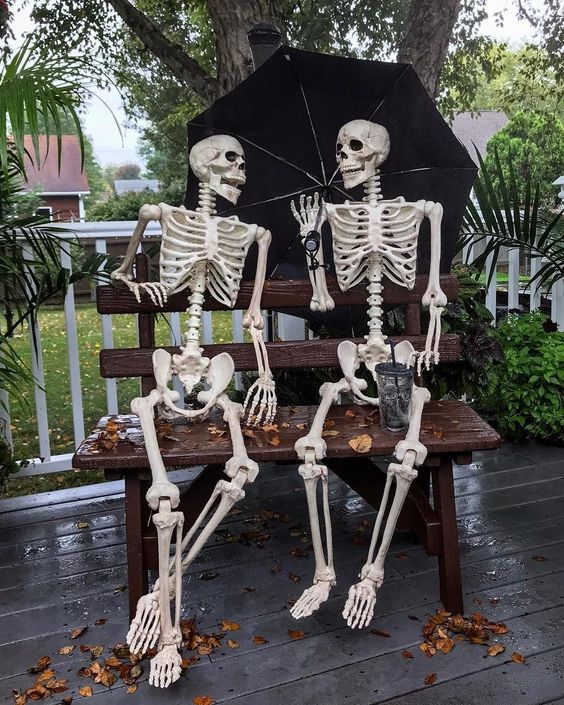 a simple and lovely fall skeleton scene with an umbrella, some fall leaves and drinks is a cool idea for Halloween