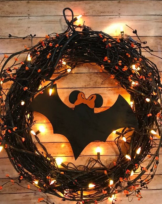 a black vine Halloween wreath with lights, orange blooms, a large black paper bat is a cool solution to DIY easily